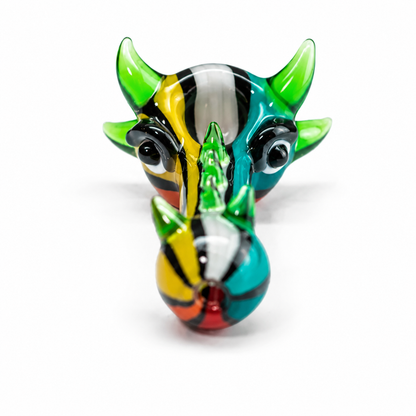A colorful glass sculpture of a rhinoceros head, featuring vibrant green, blue, yellow, red, and black patterns, set against a plain white background.