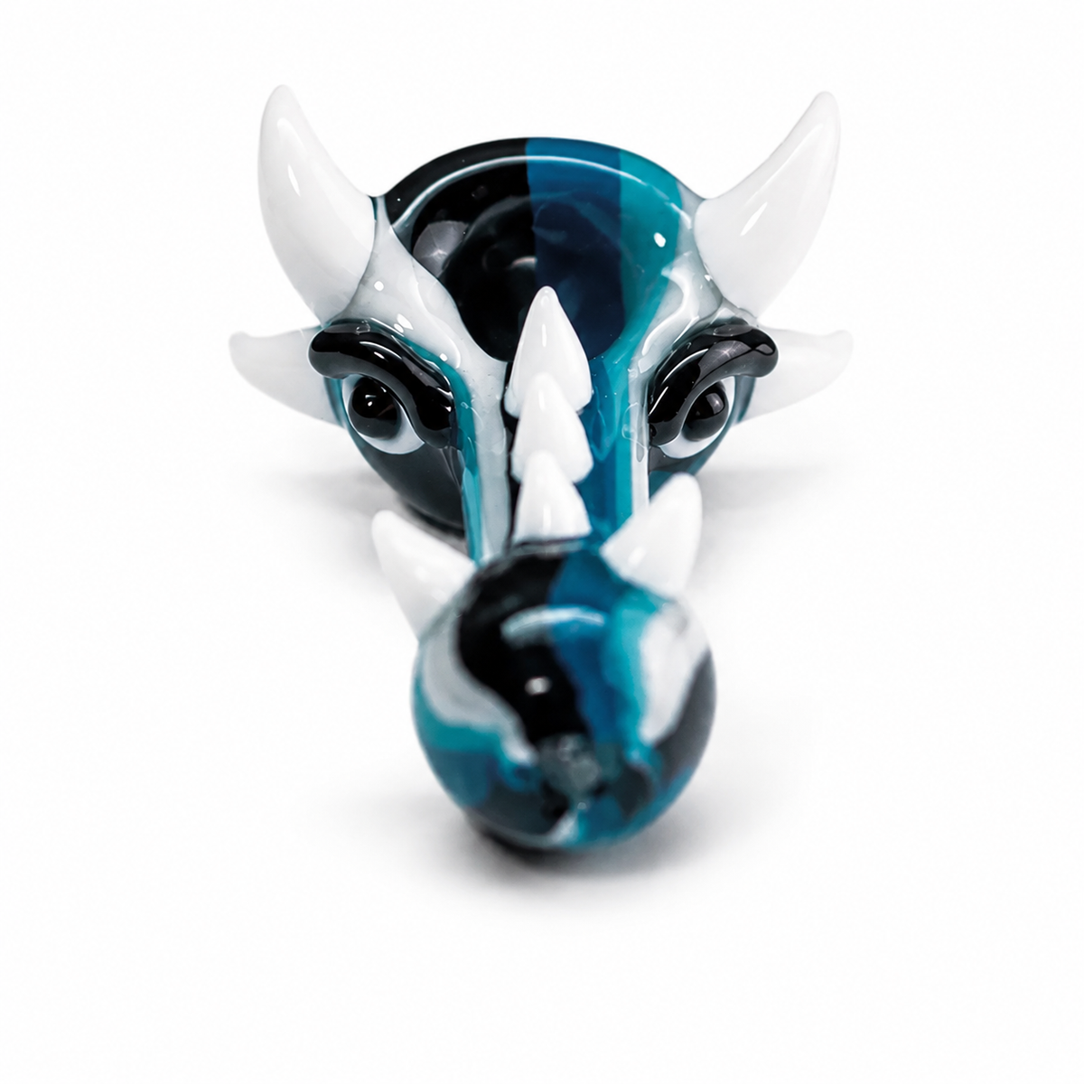 A stylized glass figurine of a horned animal head, likely a bull or ram, with swirling blue, black, and white glass. The figurine is photographed on a seamless white background.