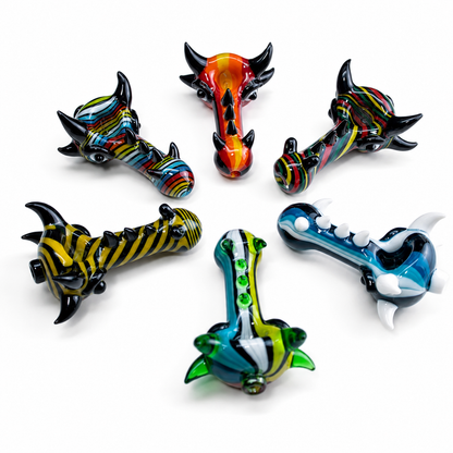 Six hand-blown glass dragon-shaped pipe pieces arranged in a circle on a white background, each with unique colorful patterns including black and yellow stripes, red and orange gradients, blue and white details, and green accents.